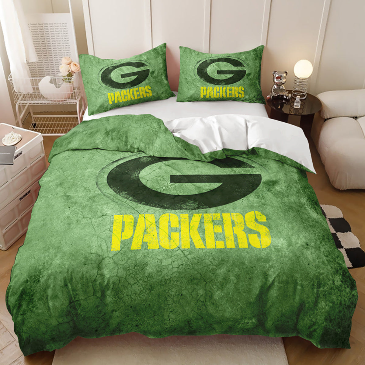 A bed dressed in a Green Bay Packers-themed bedding set, featuring a green duvet cover with a large distressed green and yellow Packers logo, two matching green pillows with the Packers logo